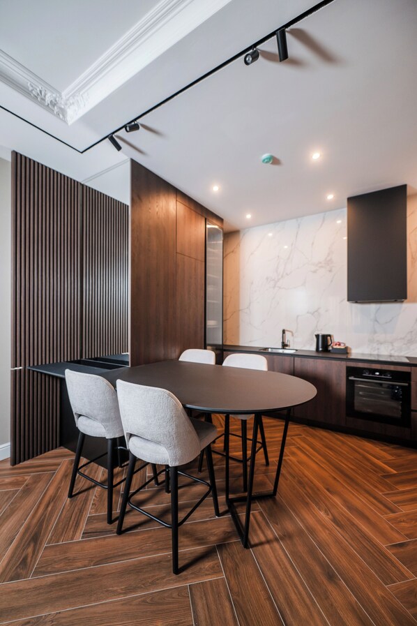 A modern kitchen with a marble backsplash, wooden cabinets, and a dining area with a round table and four chairs.