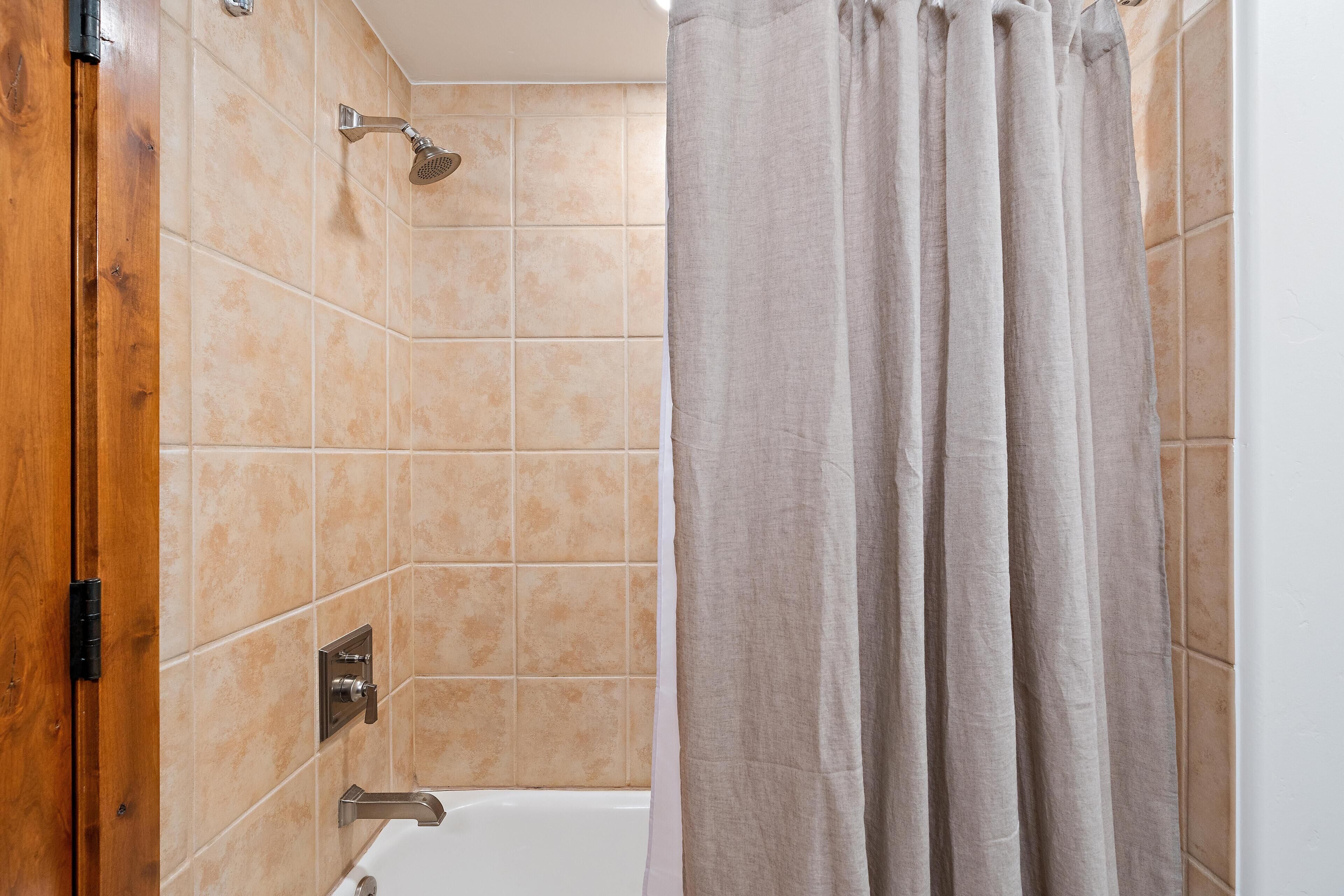 A bathroom with a shower, a bathtub, and a curtain.