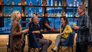 A bar area with wooden floors and a bar counter. There are multiple bottles of liquor on shelves behind the bar. - Lodge Studio | Exclusive Tamarack Perks (Tamarack)