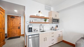 A compact kitchen with a built-in microwave, a coffee maker, and a sink. - Moonlit Oak | Includes Two 1-Day Lift Tickets (Tamarack)