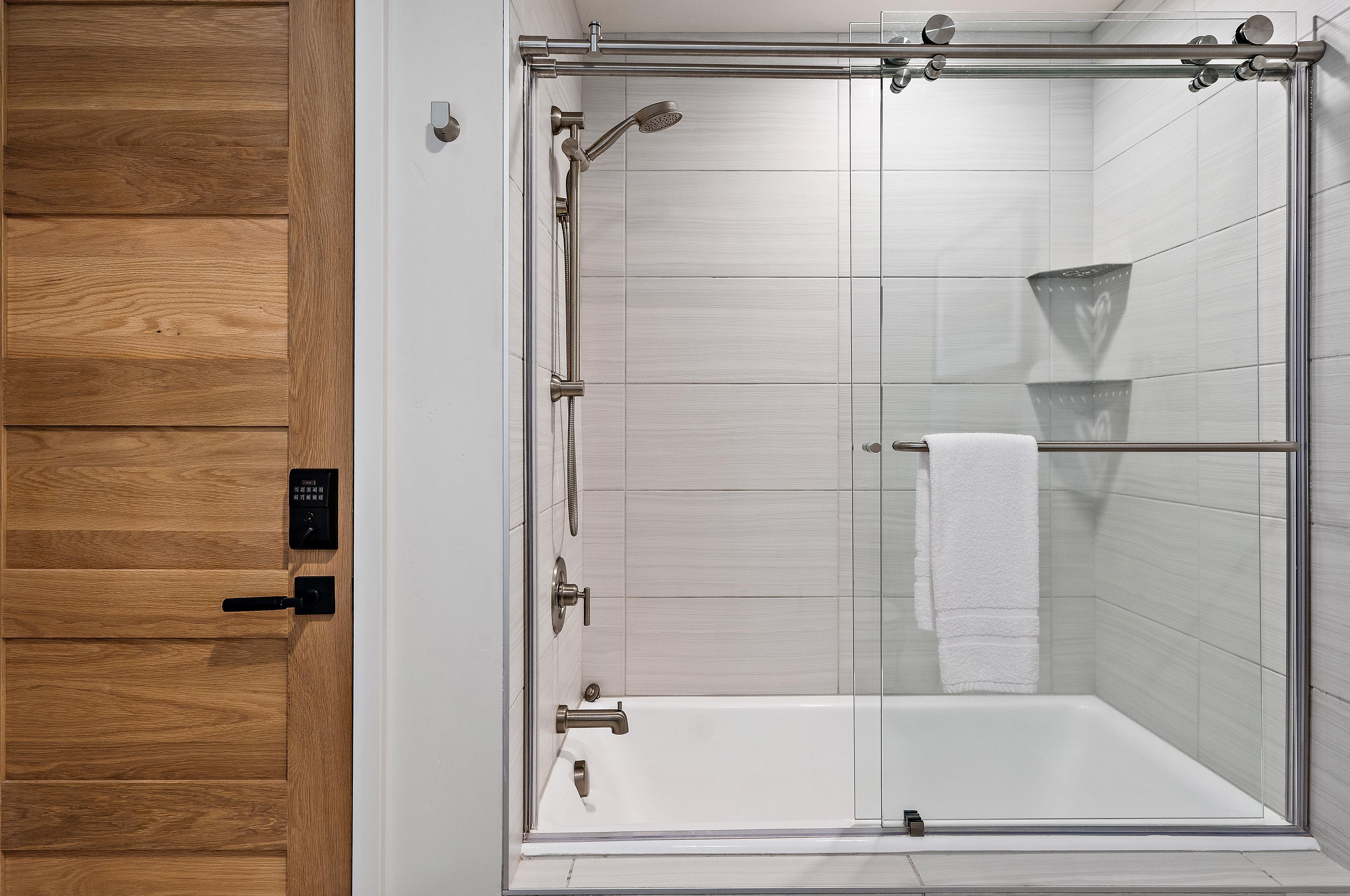 A modern shower enclosure with a glass door, a control panel, and a towel rack.