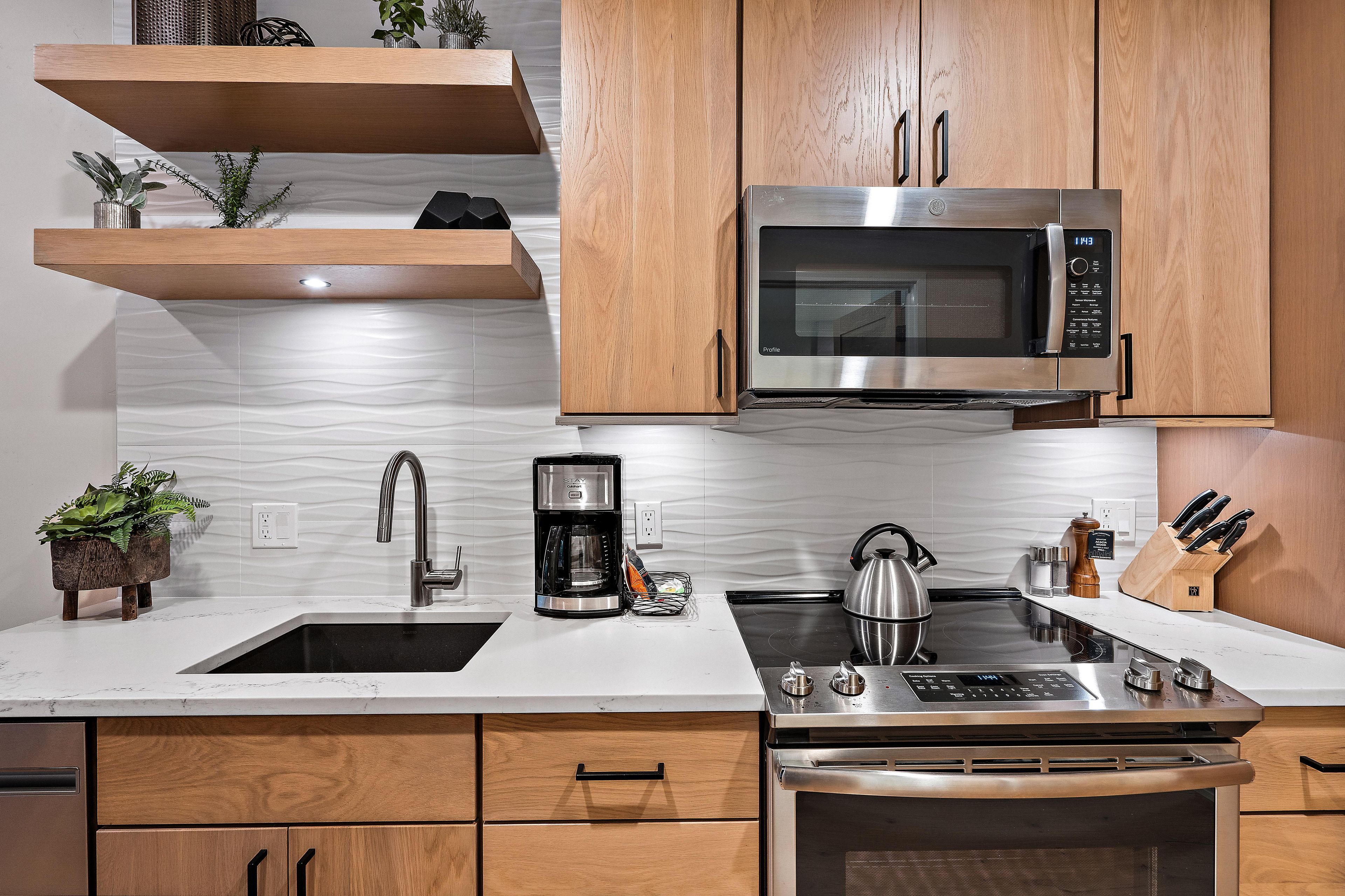 A modern kitchen with a stainless steel range, a built-in microwave, and a coffee maker.