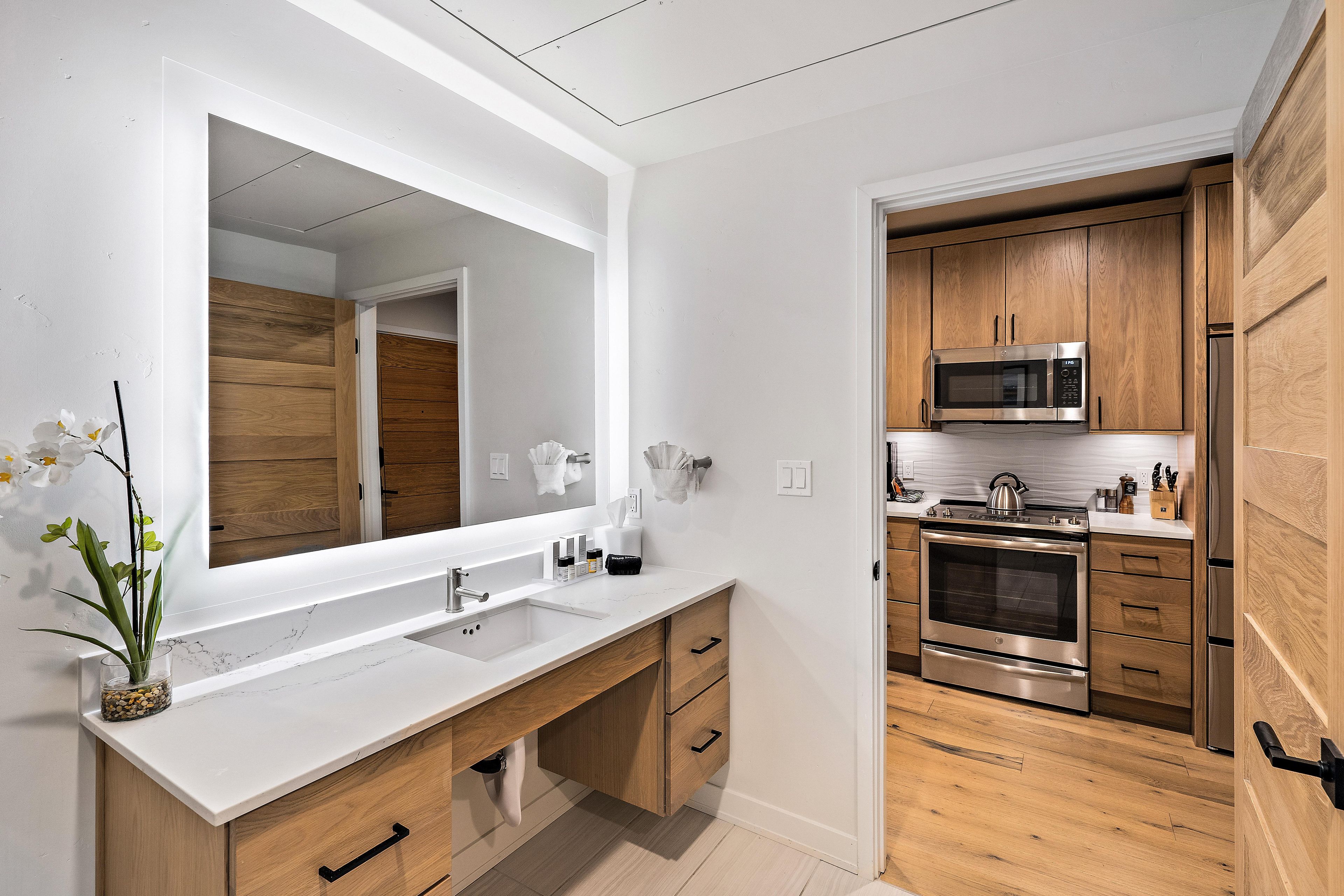 A modern kitchen with stainless steel appliances, wooden cabinets, and a white countertop.