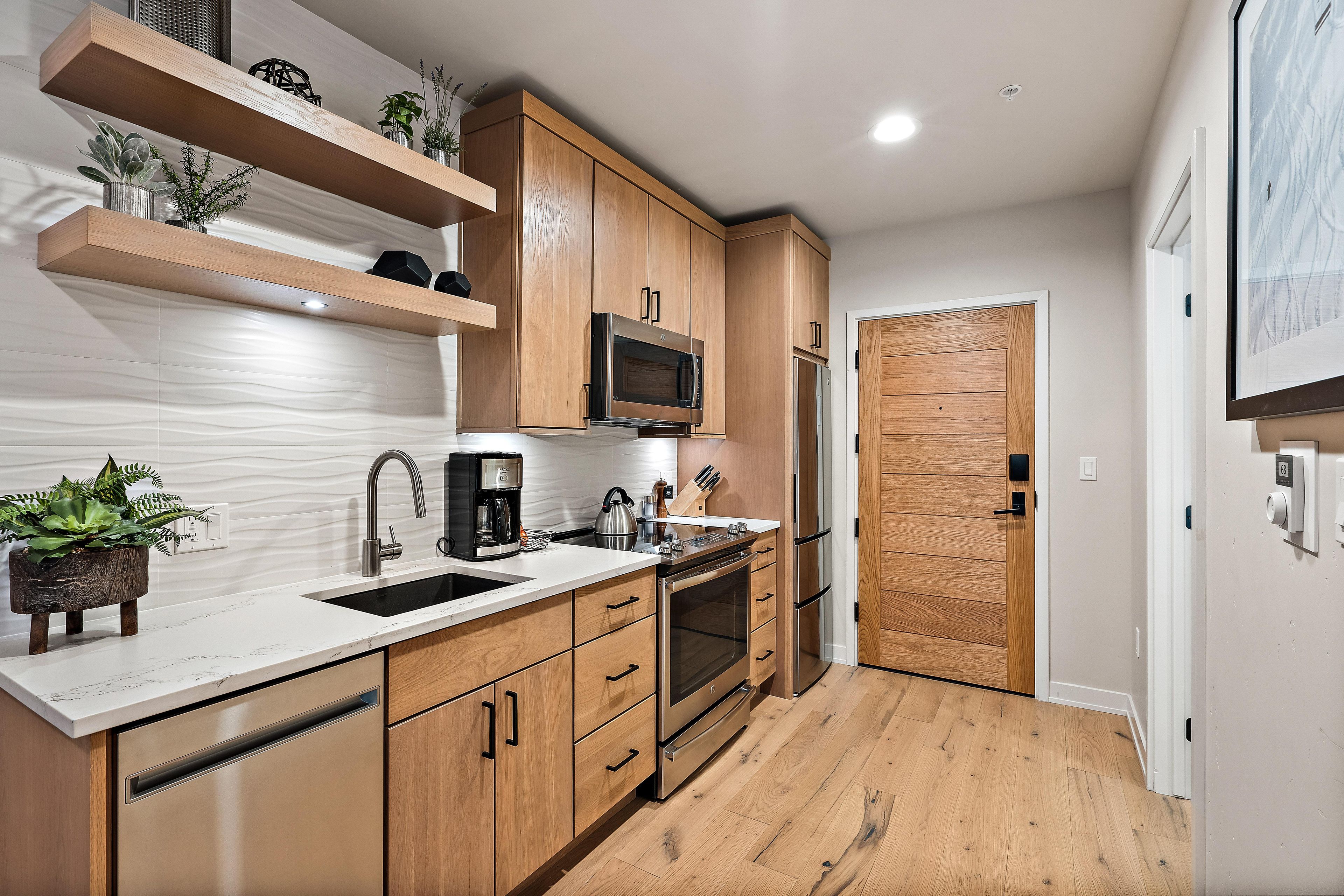 Une cuisine moderne avec des meubles en bois, des appareils en acier inoxydable et un plan de travail en marbre.