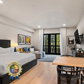 A modern bedroom with a bed, sofa, and a dining area with a table and chairs. - Polished Condo|Centrally Located with Village Views (Tamarack)