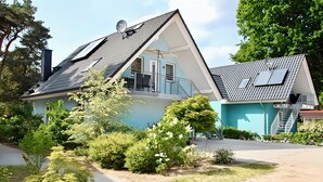 Une maison moderne avec un toit en pente, un balcon et des panneaux solaires.