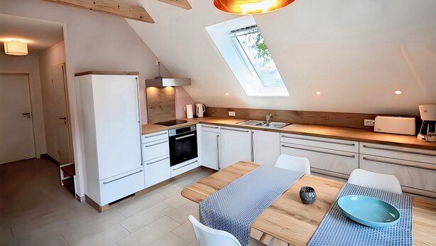 Une cuisine moderne avec des meubles blancs, un plan de travail en bois et une lucarne.