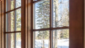 A window with a view of a snowy landscape and tall trees. - Four Reasons | Exclusive Tamarack Perks (Tamarack)
