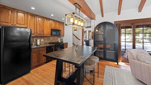 A modern kitchen with wooden cabinets, a black refrigerator, and a central island. - Four Reasons | Exclusive Tamarack Perks (Tamarack)