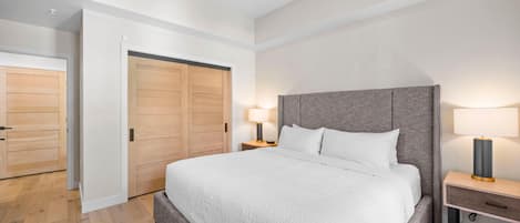Un dormitorio moderno con una cama grande, un armario de madera y lámparas de noche.