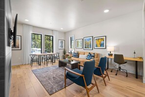Ein modernes Wohnzimmer mit einer Couch, Sesseln, einem Esstisch und Kunstwerken an den Wänden.