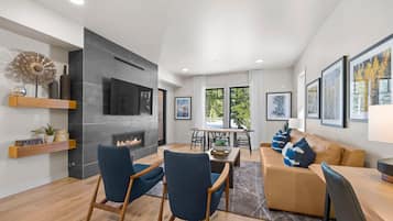A modern living room with a fireplace, a dining area, and a sofa with decorative pillows.