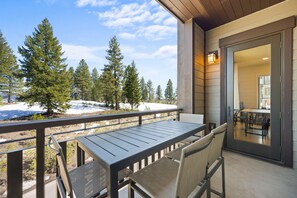 A balcony with a table and chairs, overlooking a snowy landscape with trees. - All Seasons Escape / Exclusive Tamarack Perks (Tamarack)