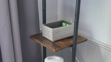 A multi-tiered wooden shelf unit with a kettle, a basket, and colorful mugs.