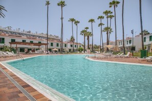 A swimming pool with lounge chairs and palm trees. - Vacation at 'El Caserío De Merengue' with Shared Pool, Wi-Fi, and Air Conditioning (Maspalomas)