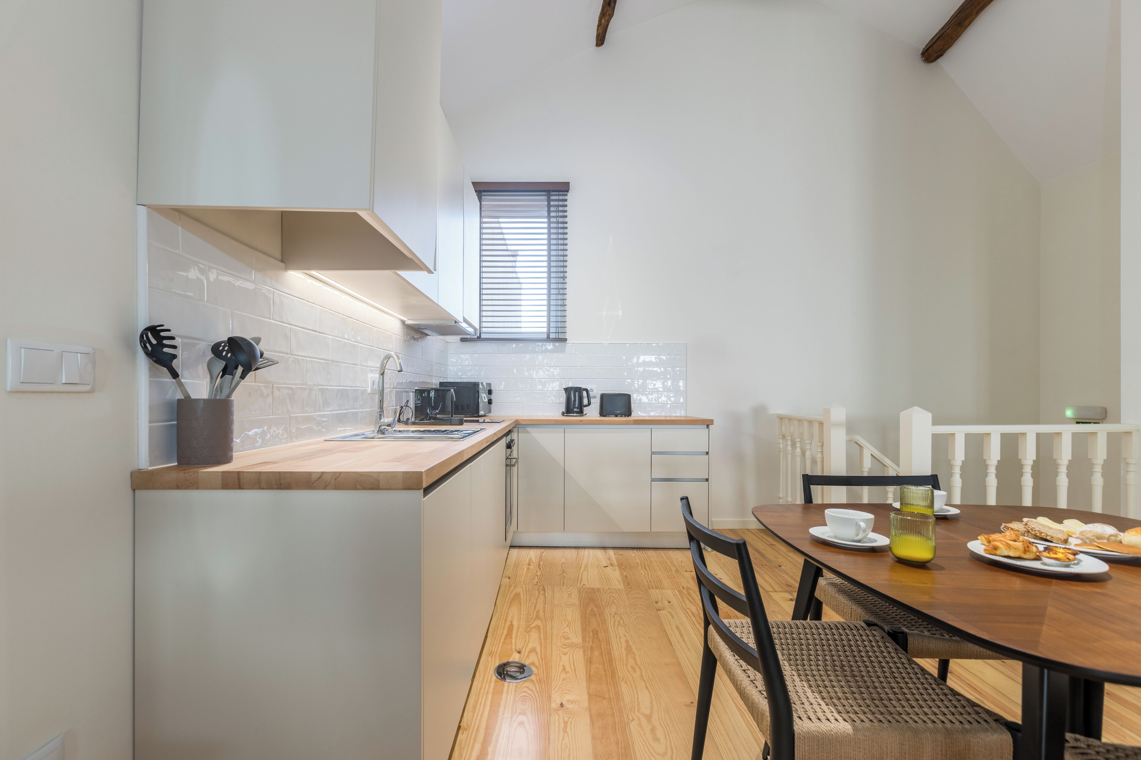 Une cuisine compacte avec un plan de travail en bois, une table à manger avec des chaises et une fenêtre au-dessus de l’évier.