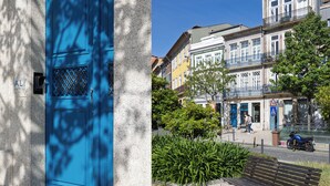 A blue door with a metal grille, a bench, and a street with buildings and a motorcycle. - Albertina Carlos Alberto By Aspasios (Porto)