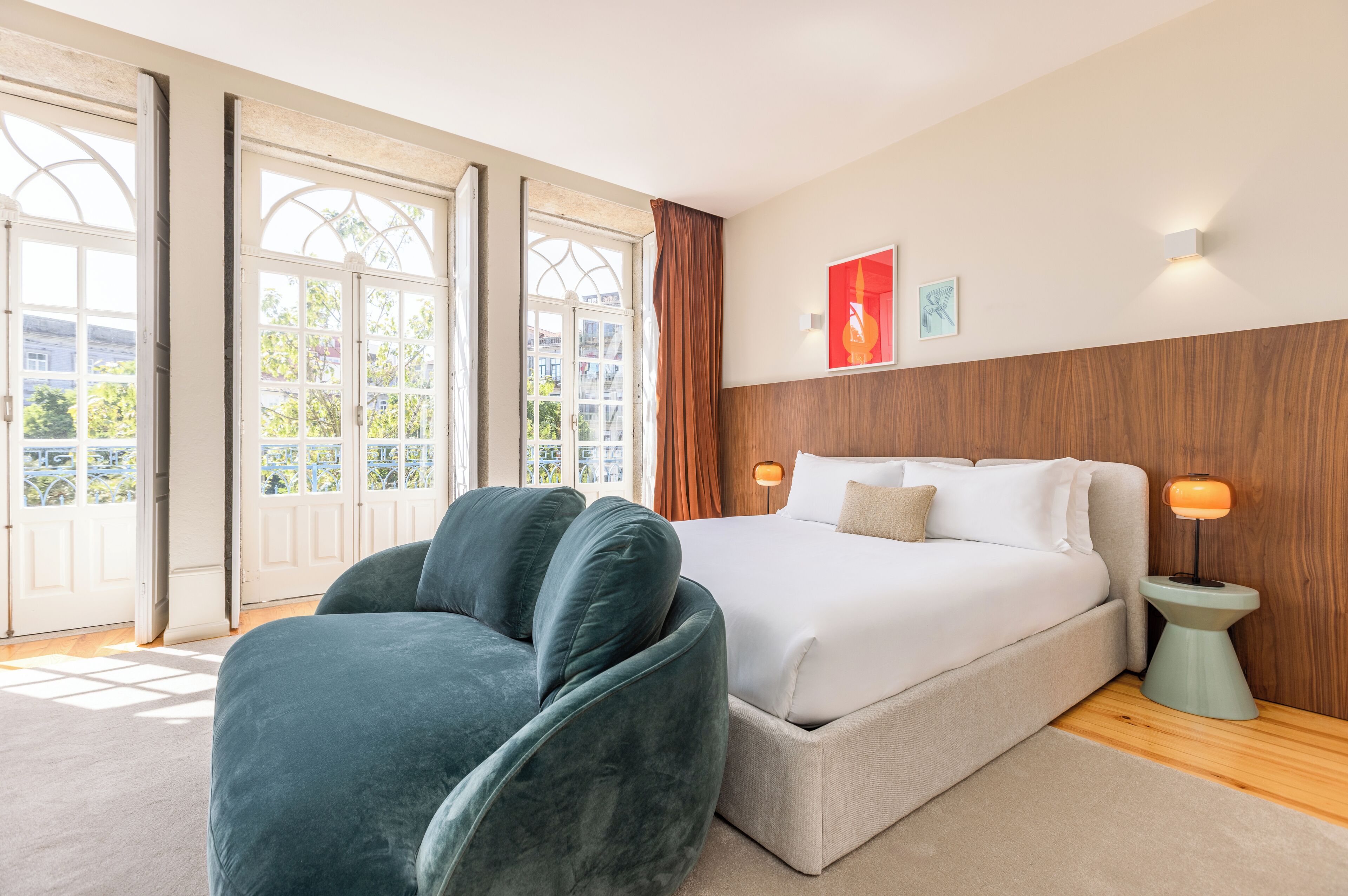 Une chambre avec un grand lit, une chaise, une table de chevet et une fenêtre avec des rideaux.