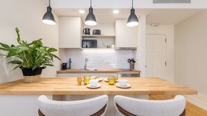 A modern kitchen with a wooden island, white cabinetry, and pendant lighting. - Albertina Carlos Alberto By Aspasios (Porto)