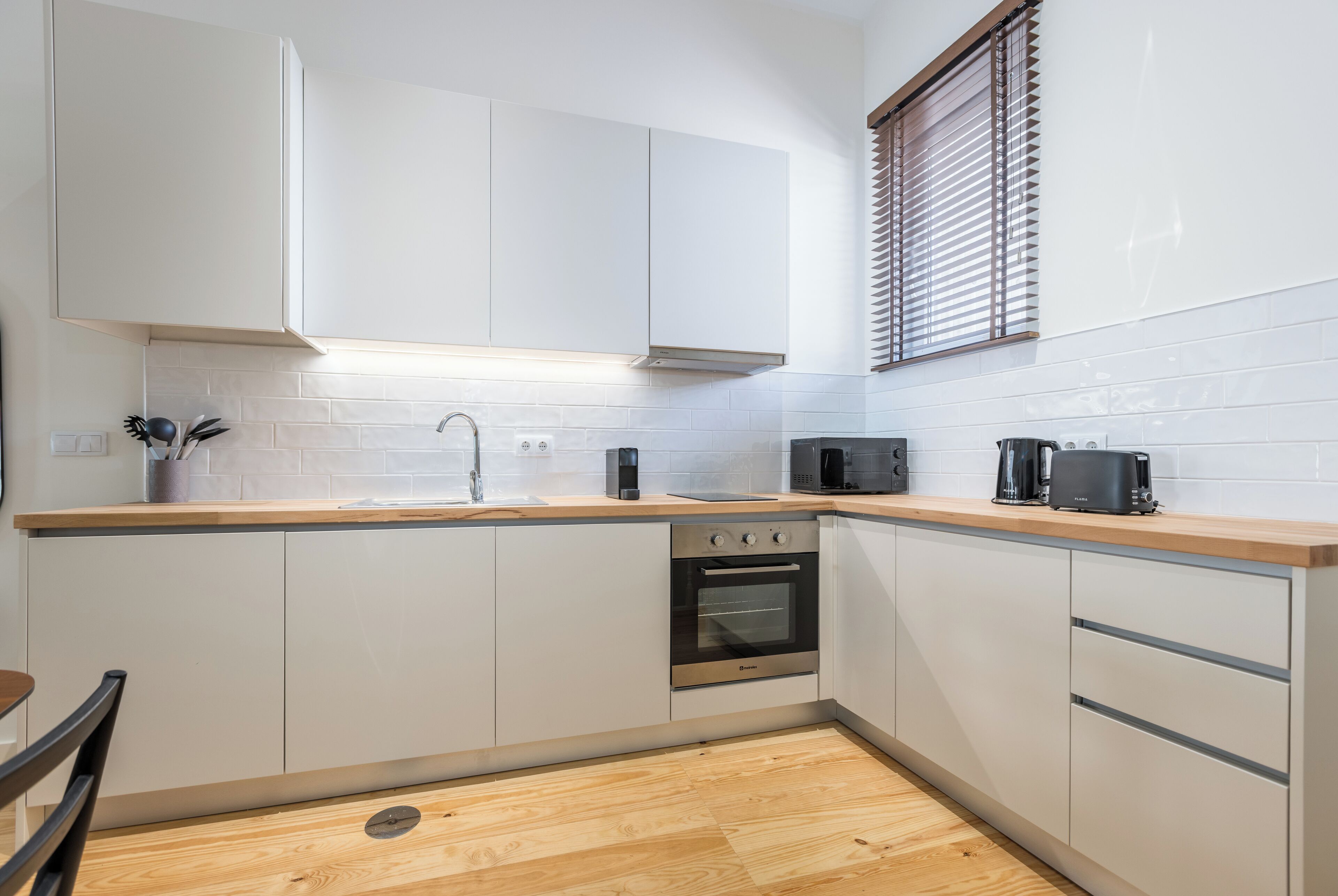 A modern kitchen with white cabinets, a stainless steel oven, a microwave, and a toaster.
