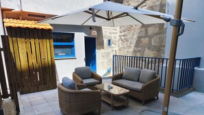 A patio area with wicker furniture, a table, and a ceiling fan. - Albertina Carlos Alberto By Aspasios (Porto)