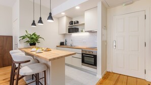 A modern kitchen with a wooden island, bar stools, a potted plant, and built-in appliances. - Albertina Carlos Alberto By Aspasios (Porto)