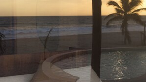 Habitació amb un llit corbat, vista a l'oceà i una palmera.