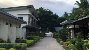 A pathway flanked by neatly trimmed hedges and a modern building with a balcony. - AltaVista Beach Resort Samal powered by Cocotel (Samal)