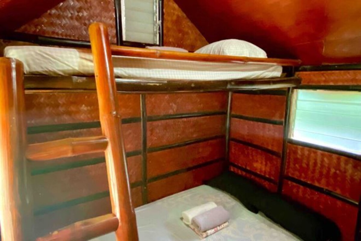 A small, compact room with a bunk bed, a single bed, and a window.