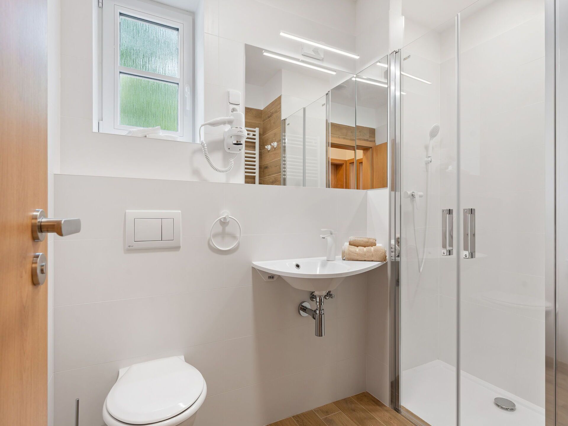 Une salle de bain moderne équipée de toilettes, d’un lavabo et d’une douche à parois de verre.