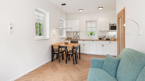 A modern kitchen with white cabinets, a dining table with chairs, and a light blue sofa. - Nice apartment for 4 guests with WIFI, TV, patio and pets allowed (Nový Bor)