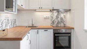 Una cocina moderna con armarios blancos, encimera de madera, campana extractora de acero inoxidable y un salpicadero decorativo.