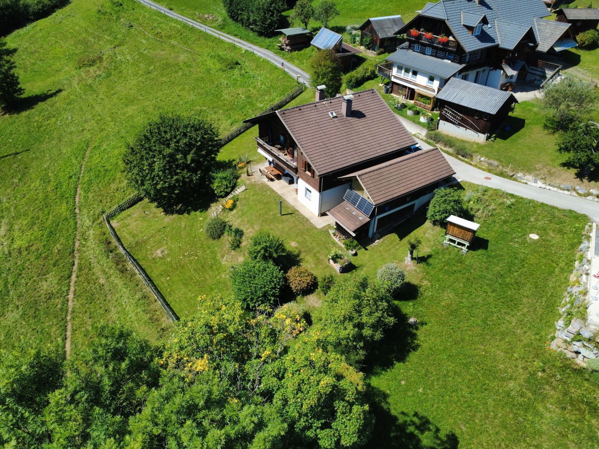 An aerial view of a residential area with houses, a paved road, and a fenced property.
