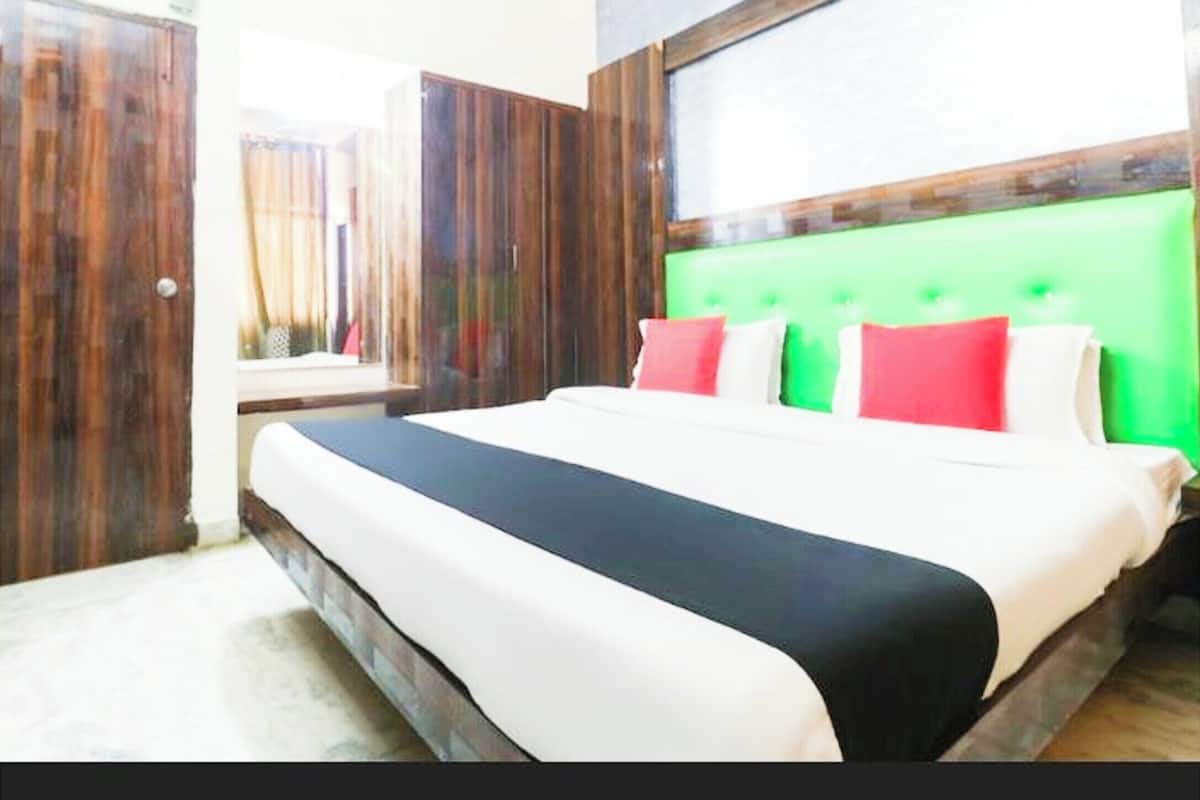 Habitació d'hotel amb un llit gran, un armari de fusta i un capçal de llit verd.