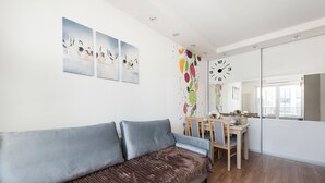 Ein modernes Wohnzimmer mit einer Couch, einem Esstisch und Kunstwerken an den Wänden.