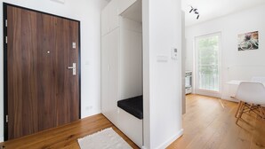 Ein modernes Interieur mit einer Holztür, weißen Wänden, einer schwarzen Bank, einem weißen Tisch und einem Kunstwerk mit einem Fahrrad.