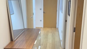 A hallway with wooden flooring, a bench, a desk, and doors leading to other rooms. - Oval House Retreat in Camden Town (London)