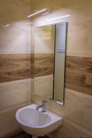 Un baño con un lavabo blanco, un espejo y una pared con diseño que imita la madera.