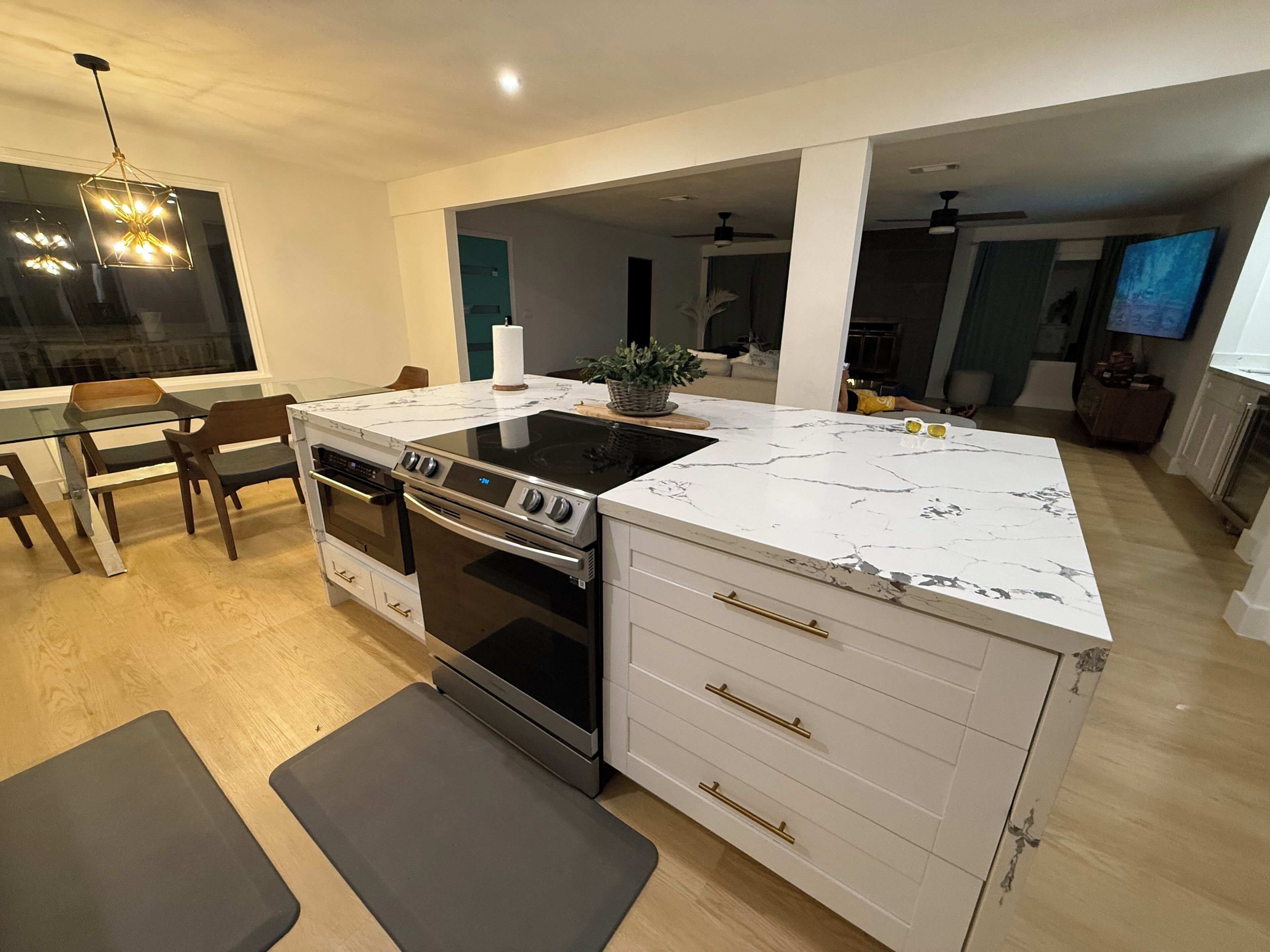 Une cuisine moderne dotée d’un four encastré, d’une plaque de cuisson et d’un plan de travail en marbre blanc.