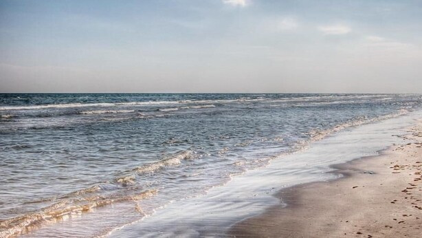 A beach with waves gently lapping onto the shore. - AZURE beach villa at Galveston  (Galveston)