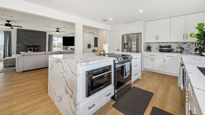 A modern kitchen with white cabinetry, a marble island, and stainless steel appliances. - AZURE beach villa at Galveston  (Galveston)