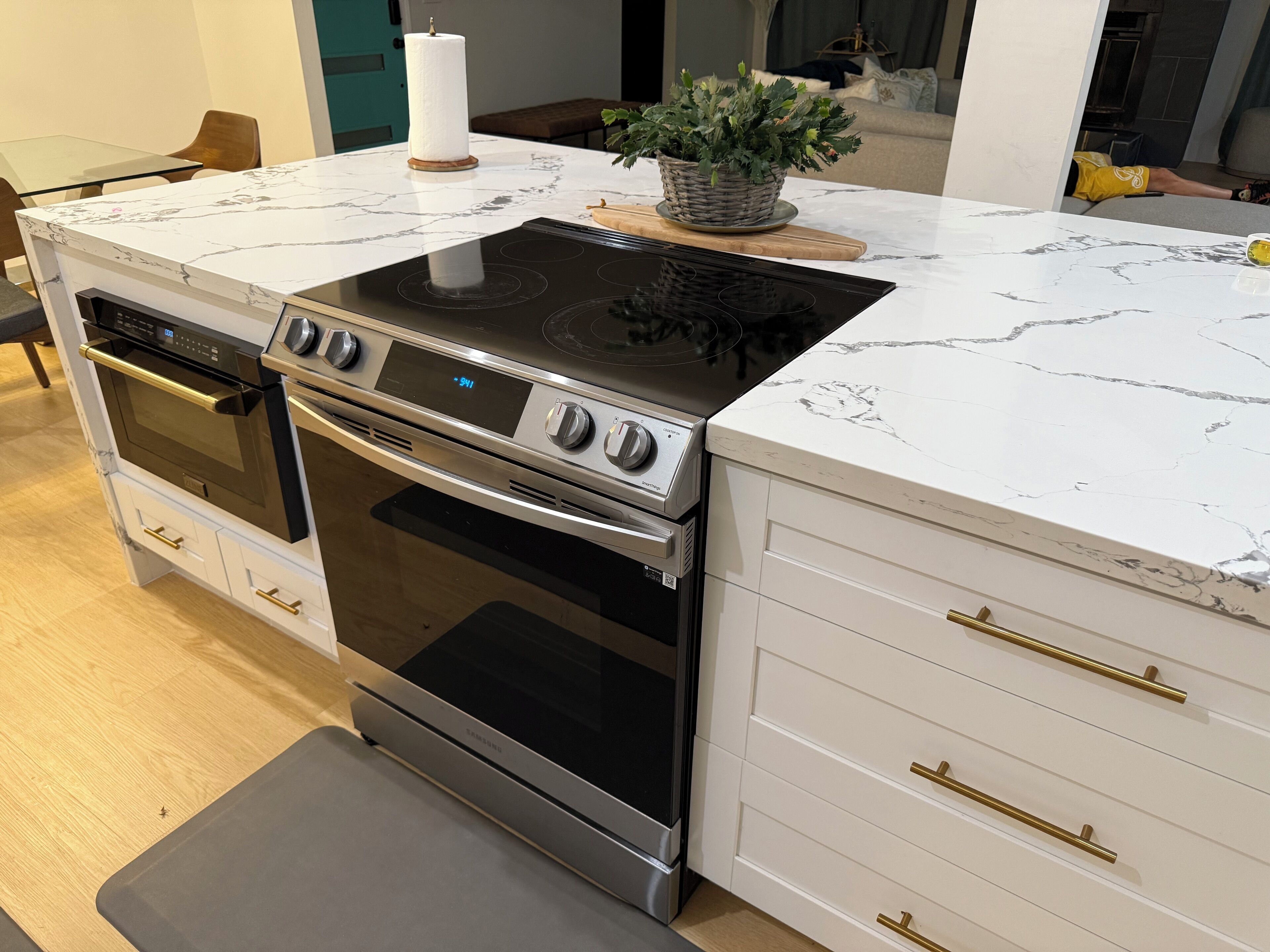 Une cuisine équipée d’un four encastré, d’une plaque de cuisson et d’un plan de travail en marbre blanc.