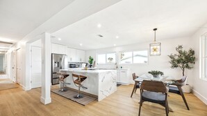 A modern kitchen with a central island, white cabinetry, and stainless steel appliances. - AZURE beach villa at Galveston  (Galveston)