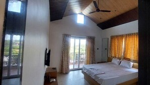 Ein Schlafzimmer mit einem großen Bett, einem Deckenventilator, einer Schiebetür zum Balkon und einer Holzzahlung.