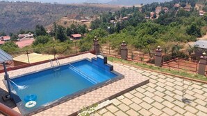 Ein Swimmingpool mit Blick auf eine an einem Hang gelegene Siedlung.