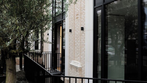 Un bâtiment doté de grandes fenêtres, d’une façade en briques et d’une rambarde en métal noir.