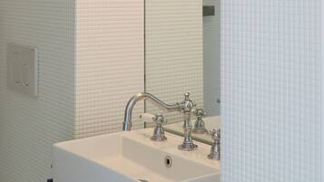 A bathroom with a white sink, a mirror, and a light fixture above the mirror.