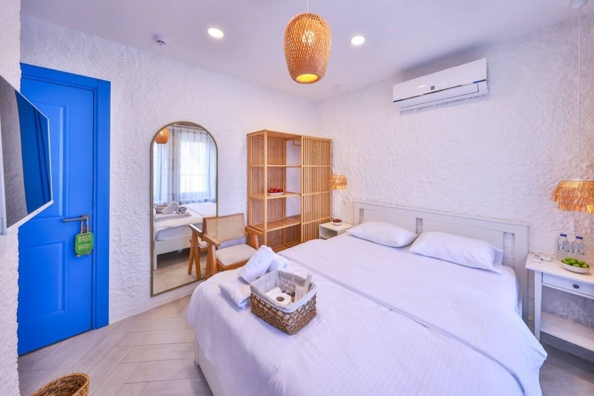 Ein Hotelzimmer mit einem großen Bett, einem Schreibtisch mit Stuhl, einem Kleiderschrank und einem Badezimmerspiegel.