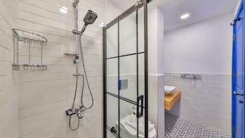 Een moderne badkamer met een douchecabine van glas, witte betegelde wanden, een vloer met patroon en een blauwe deur.