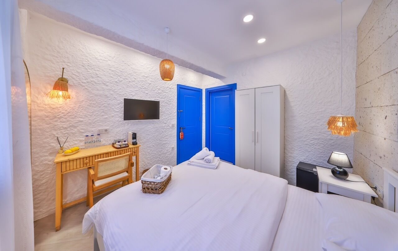 Une chambre à coucher avec un lit, un bureau, une chaise, une armoire et deux portes bleues.